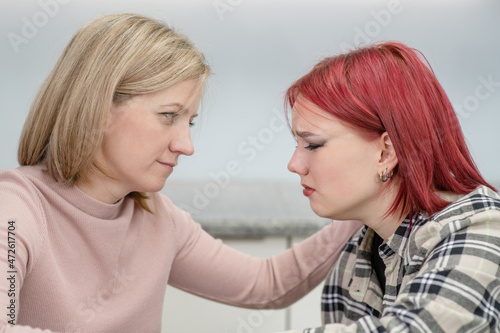 Careful woman and teen girl sit at home, worried parent calms crying girl. Teenagers problem concept