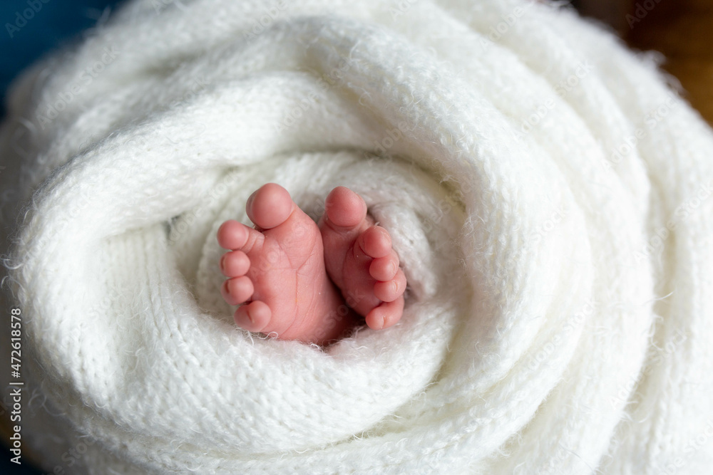 a small leg of the newborn in a white scarf. soft focus a small leg of the newborn in a white scarf. soft focus
