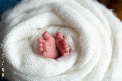 a small leg of the newborn in a white scarf. soft focus © Svetlana