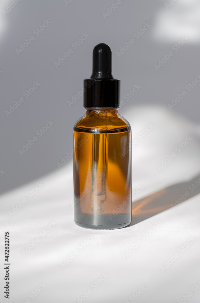 Cosmetic bottle with a pipette on a white background with beautiful shadows. Cosmetics for skin care