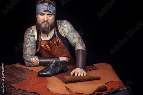 Professional Tanner working with leatherwork at the workplace photo