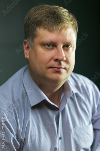Portrait of an adult male lawyer on a black background in a blue shirt.