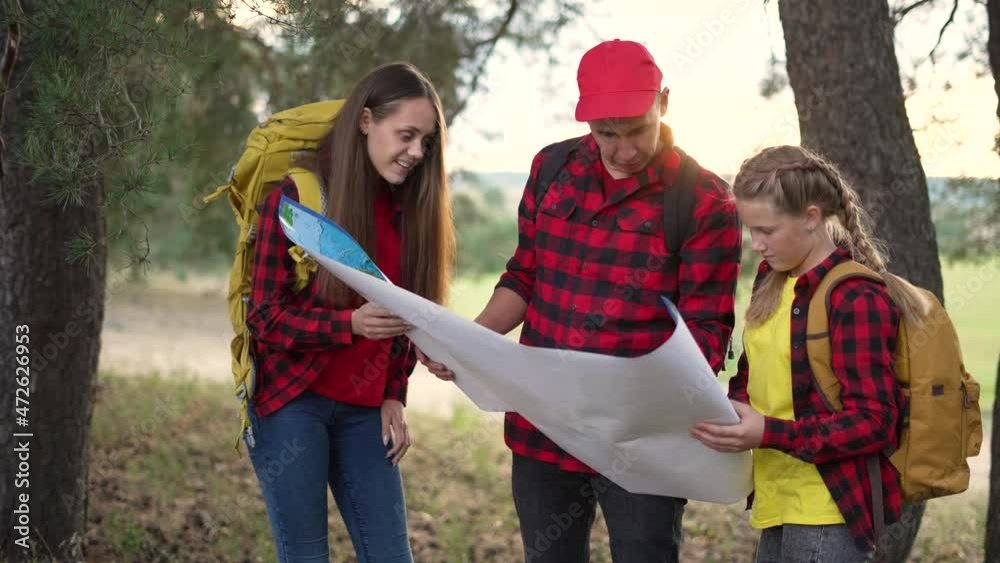 Family tourism with map in forest. Team orienteering in forest. Family travel with map. Teamwork concept. Team of tourists in a forest park with a map. Tourists hiking. Family travel in forest park