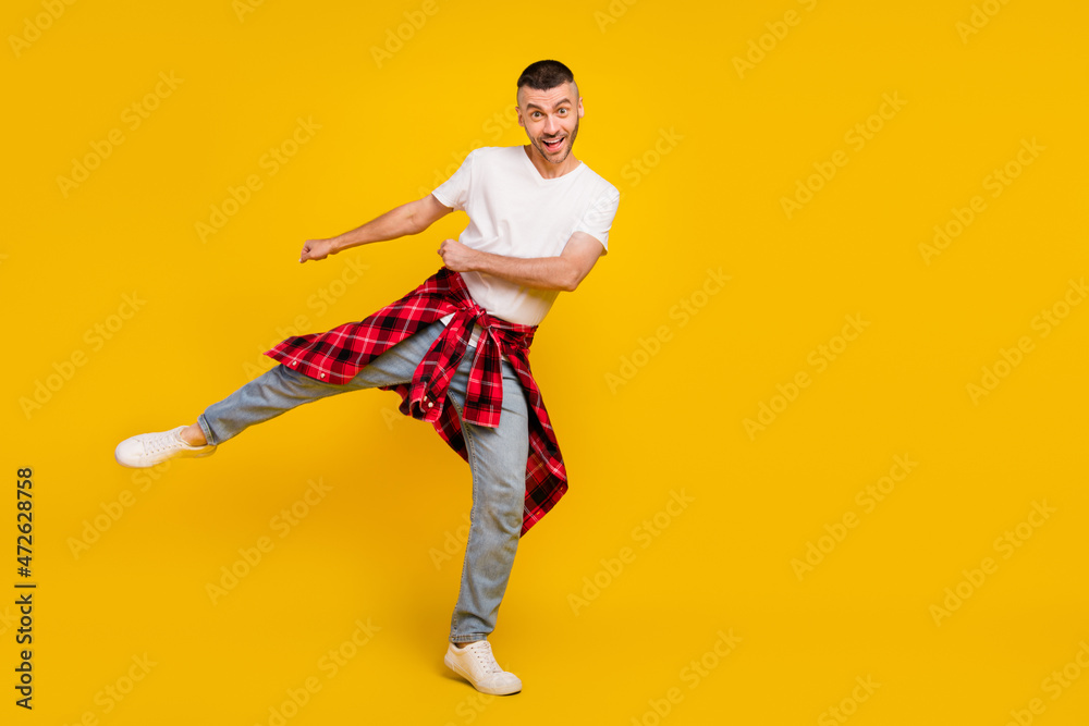 Full body photo of young amazed man wear checkered shirt on waist empty space dance isolated on yellow color background Full body photo of young amazed man wear checkered shirt on waist empty space dance isolated on yellow color background
