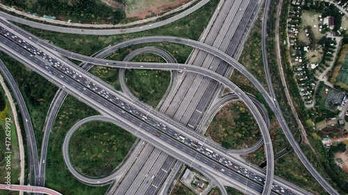 Top down aerial view from drone on modern traffic junction of multiple lane highway road in metropolis city. Heavy traffic on motorways. Elevated curved roads, clover shape bridge with no speed limit.