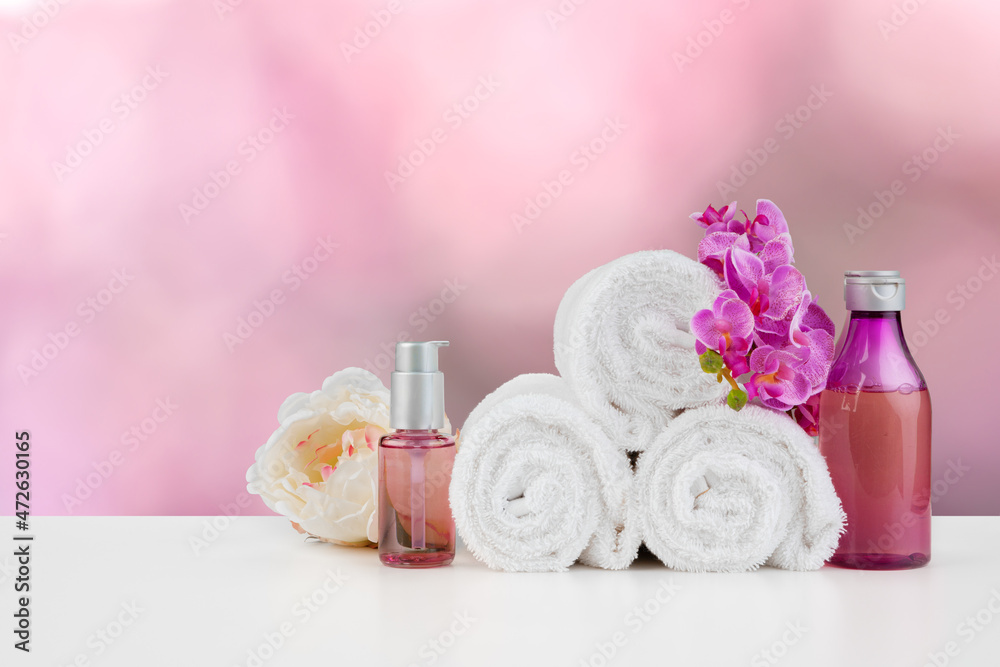 Towels with flowers on light table against blurred background Towels with flowers on light table against blurred background