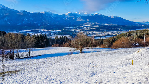 A snowy mountain landscape. Beautiful and sunny winter day, lots of snow everywhere. Bare branches of trees. Winter wonderland. Winter playground. The peaks of the mountains covered with snow.