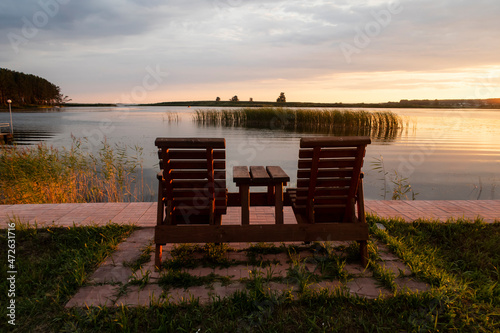 Two wooden chairs on the bank of the Ob River in Siberia at sunset
