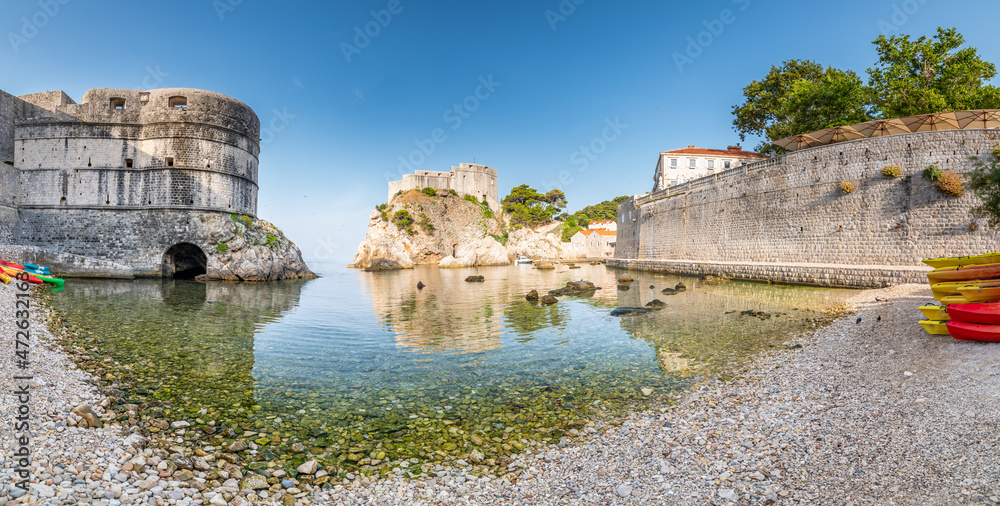 View of small water bay near old city of Dubrovnik. Ancient fort Lovrijenac near small harbor with boats. Sunny day.