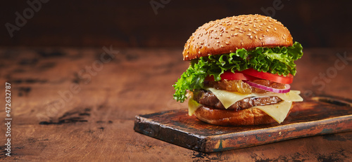 Homemade burger with beef, cheese and onion marmalade on a wooden board. Fast food concept, american food