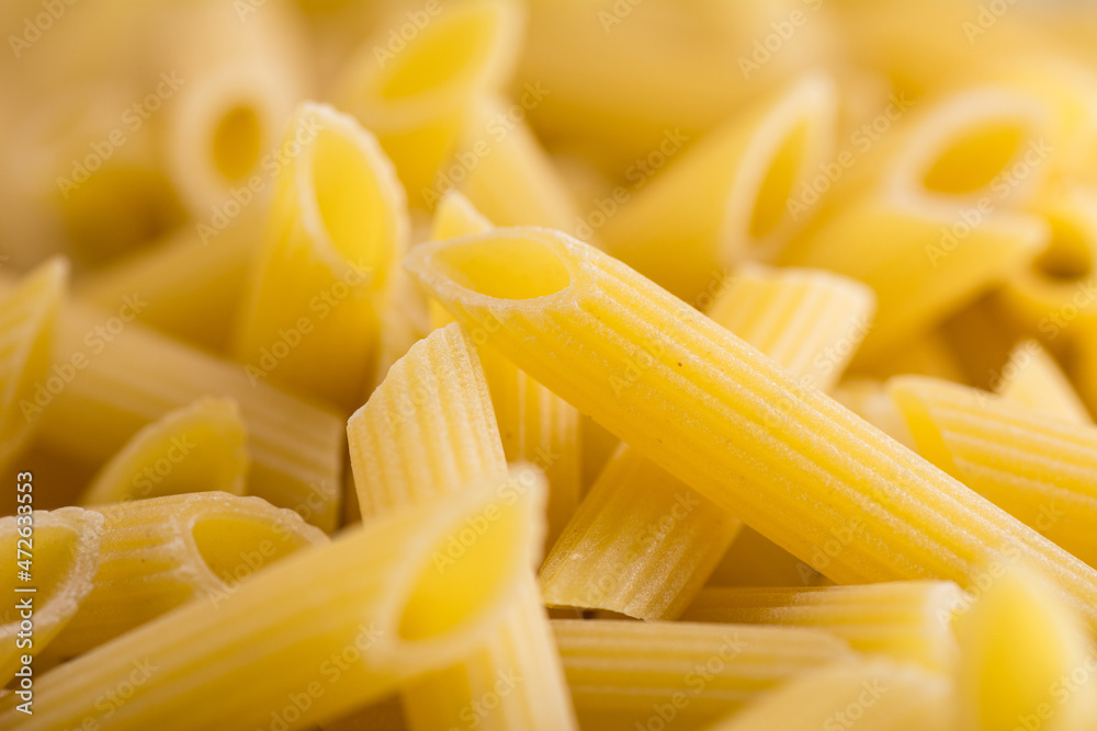 Uncooked penne pasta background. Close-up Uncooked penne pasta background. Close-up