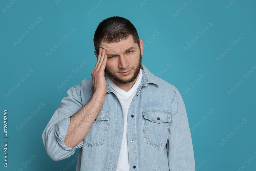 Man suffering from headache on light blue background Man suffering from headache on light blue background