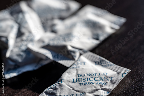 packets of desiccant scattered on a dark surface photo