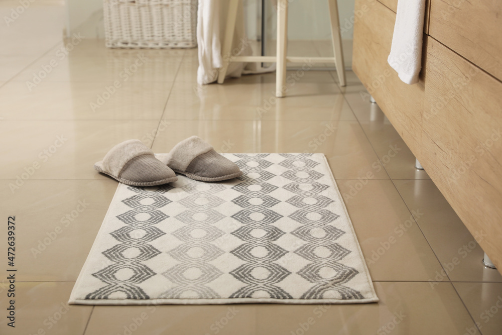 Soft bath mat and slippers on floor indoors - obrazy, fototapety, plakaty 