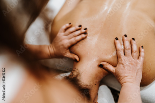 Woman receiving back massage from professional masseur in spa salon