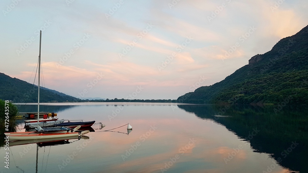 Boats in Lago Mergozzo at sunset, reflection of mountain in water. Piedmont, Northern Italy. Boats in Lago Mergozzo at sunset, reflection of mountain in water. Piedmont, Northern Italy.