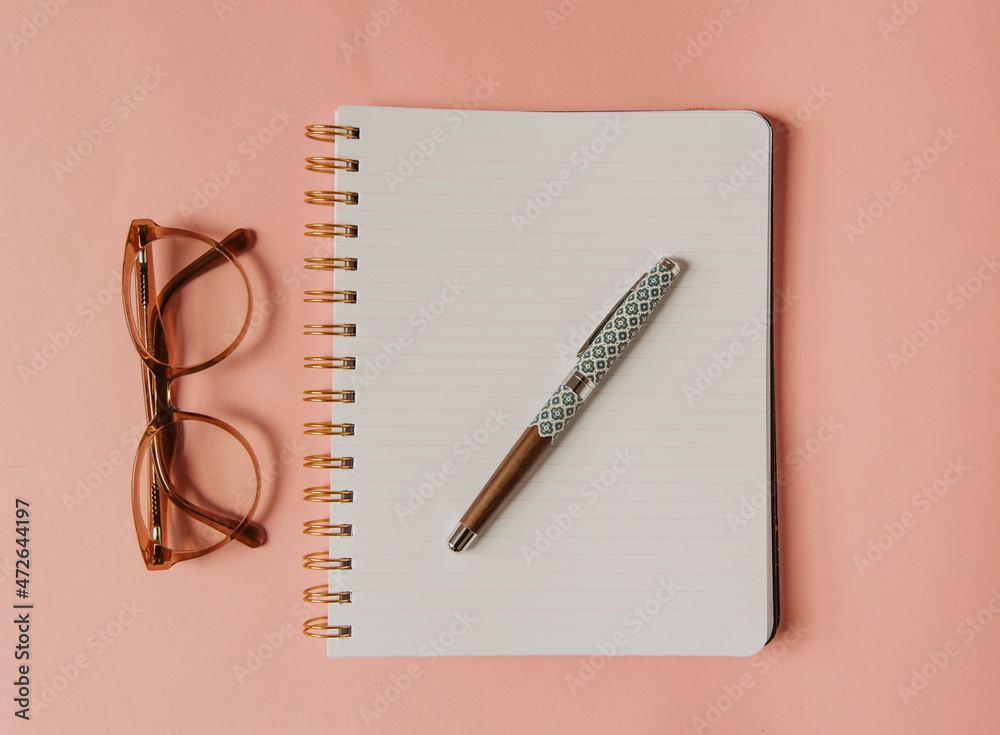 Cahier ouvert, stylo plume et lunettes sur fond rose - inspiration pour