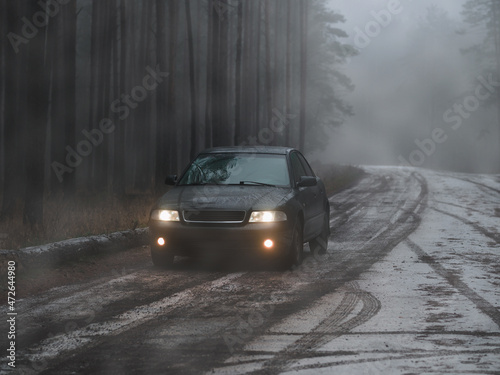 A car in a thick fog on a forest road