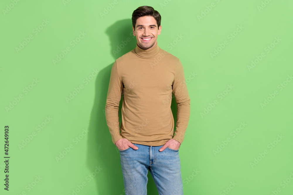 Photo of satisfied glad young man put hands in pockets look camera isolated on green color background Photo of satisfied glad young man put hands in pockets look camera isolated on green color background