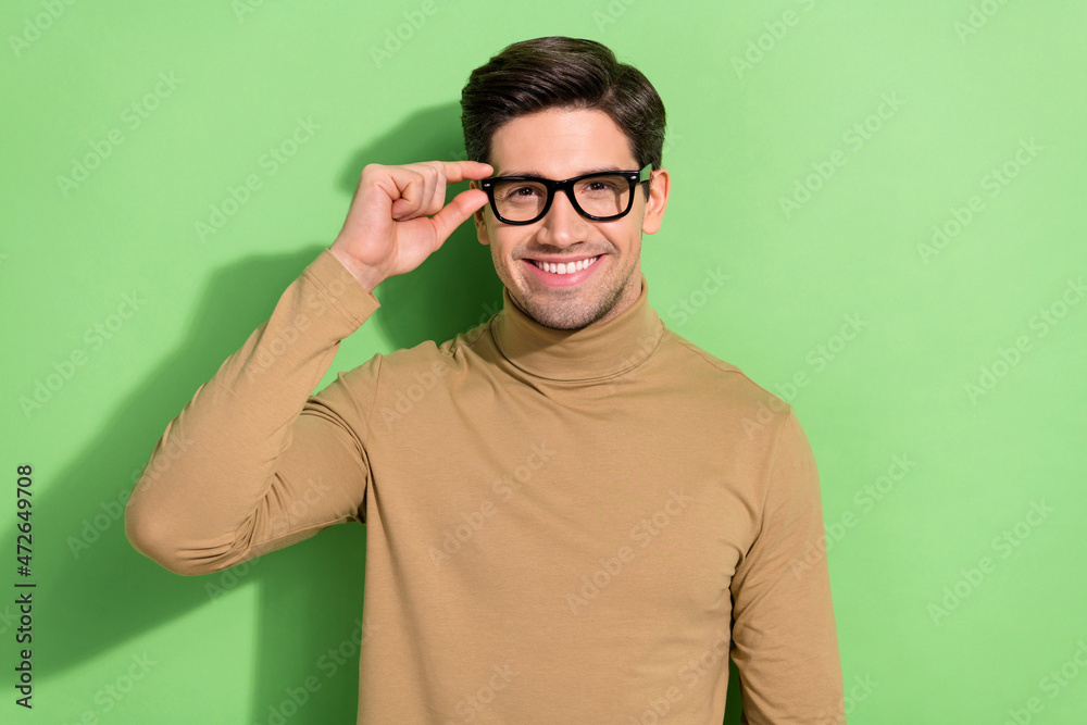 Photo of satisfied man hand touch glasses beaming smile look camera isolated on green color background Photo of satisfied man hand touch glasses beaming smile look camera isolated on green color background