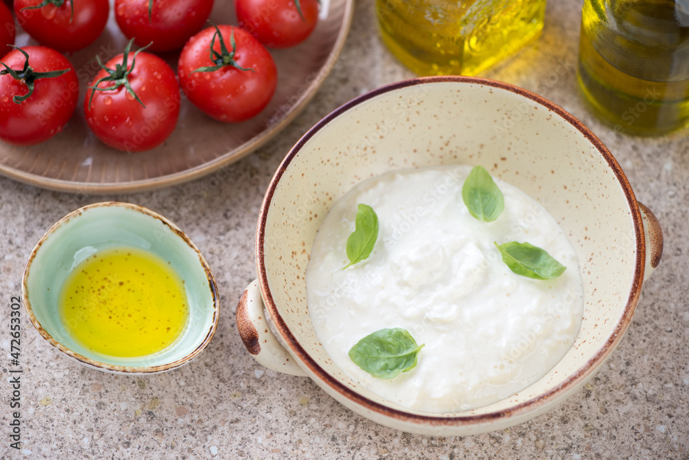 Bowl of stracciatella di bufala or italian cheese produced from buffalo milk, horizontal shot on a beige marble background Bowl of stracciatella di bufala or italian cheese produced from buffalo milk, horizontal shot on a beige marble background
