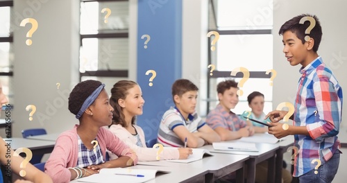 Digital composite of question marks over schoolboy giving presentation in front of friends
