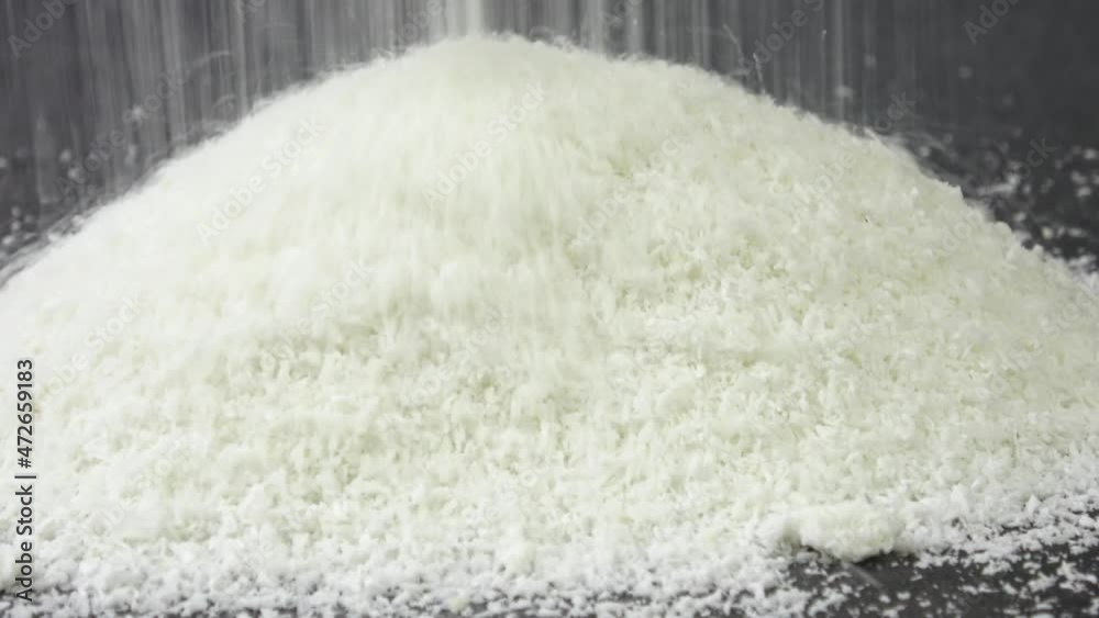 Heap of coconut flakes. Falling grated coconut on black background