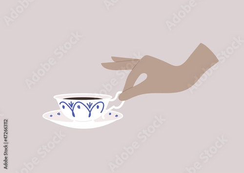 Elegant hand holding a porcelain tea cup, breakfast time