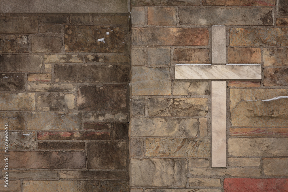 Stone cross on brick wall