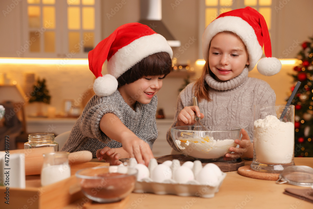 Cute little children making dough for Christmas cookies in kitchen Cute little children making dough for Christmas cookies in kitchen