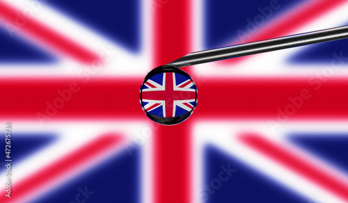 Vaccine syringe with drop on needle against national flag of United Kigdom background. Medical concept vaccination. Coronavirus Sars-Cov-2 pandemic protection. National safety idea. photo