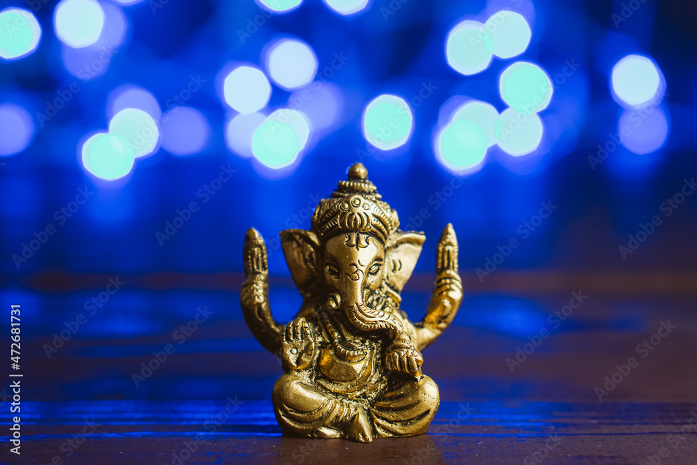 Golden lord ganesha sclupture over blue illuminated background. Celebrate lord ganesha festival