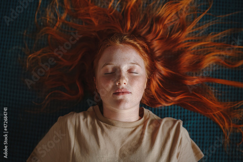 Canvastavla Young freckled redhead woman lying down eyes closed - flat lay concept portrait