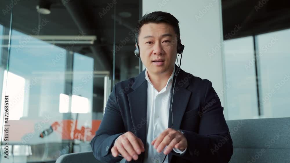 Asian business man speaker in suit with headset talking looking at camera. Online meeting, conference, distance learning, remotely training via video call in a modern office class. Webcam view Asian business man speaker in suit with headset talking looking at camera. Online meeting, conference, distance learning, remotely training via video call in a modern office class. Webcam view