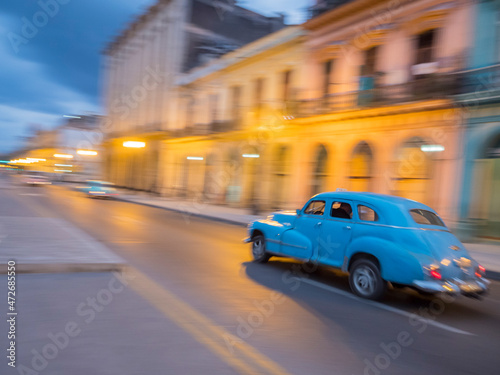 Caribbean, Cuba, Havana, Havana Vieja (Old Havana), a UNESCO World Heritage Site, classic car in motion at dusk