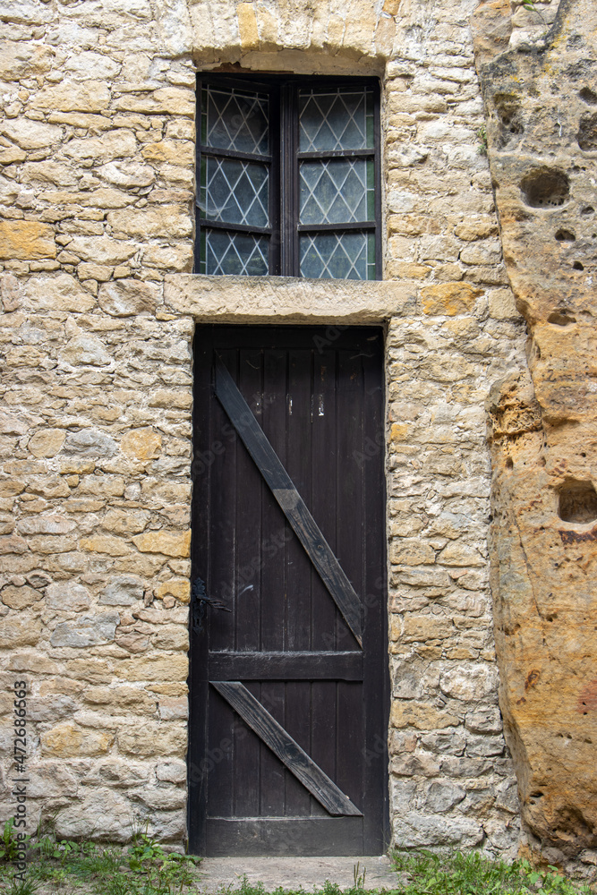 The old door with window in the stone facade of a historic building. The old door with window in the stone facade of a historic building.