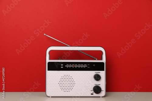 Retro radio receiver on table against red background photo