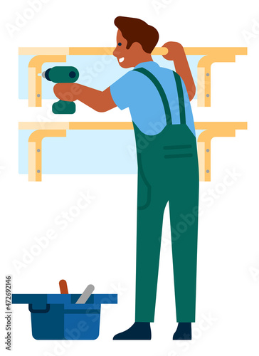 Man working with power drill. Repairman hanging shelves on wall
