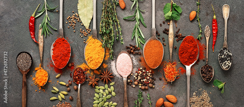 Various spices and herbs in a spoon. Dark grunge background. Top view, flat lay. Banner