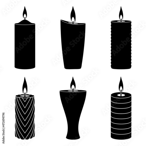 Burning paraffin candles of different shapes on a white background.