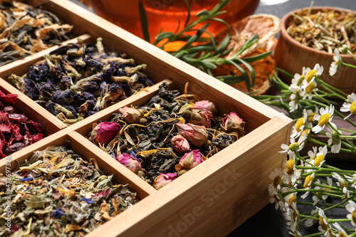 Different dry teas in wooden box and chamomile flowers on table, closeup © New Africa