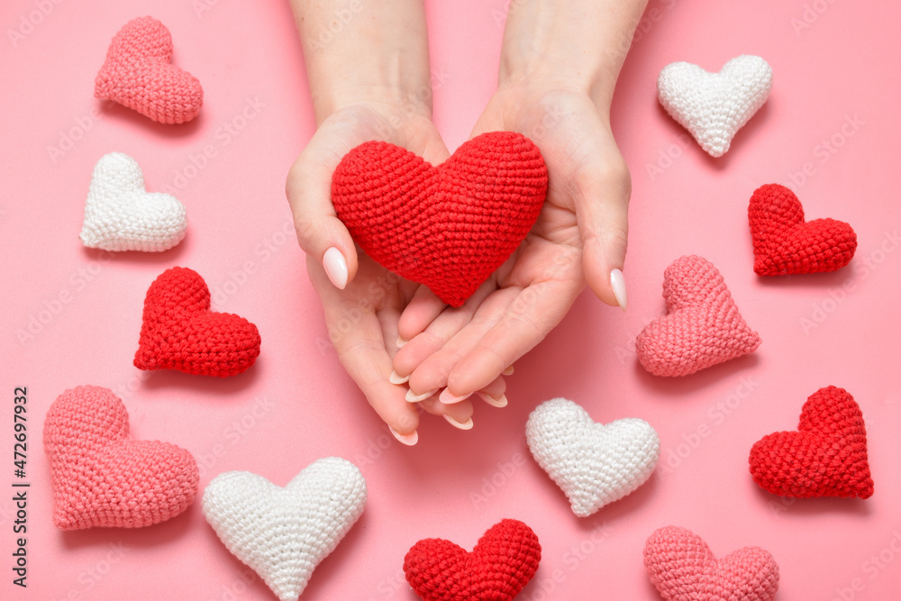 Women's hands hold a red knitted heart. Background for Valentine's Day.