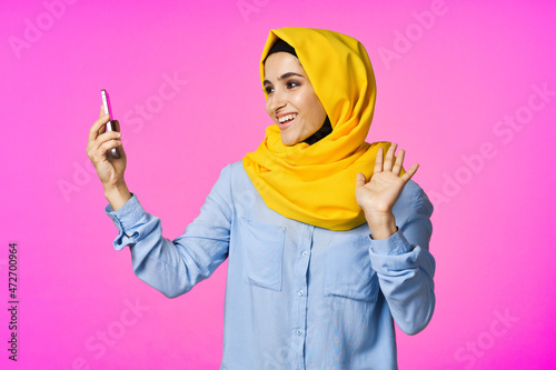 cheerful woman in a yellow hijab with a phone in her hands communication technology © VICHIZH