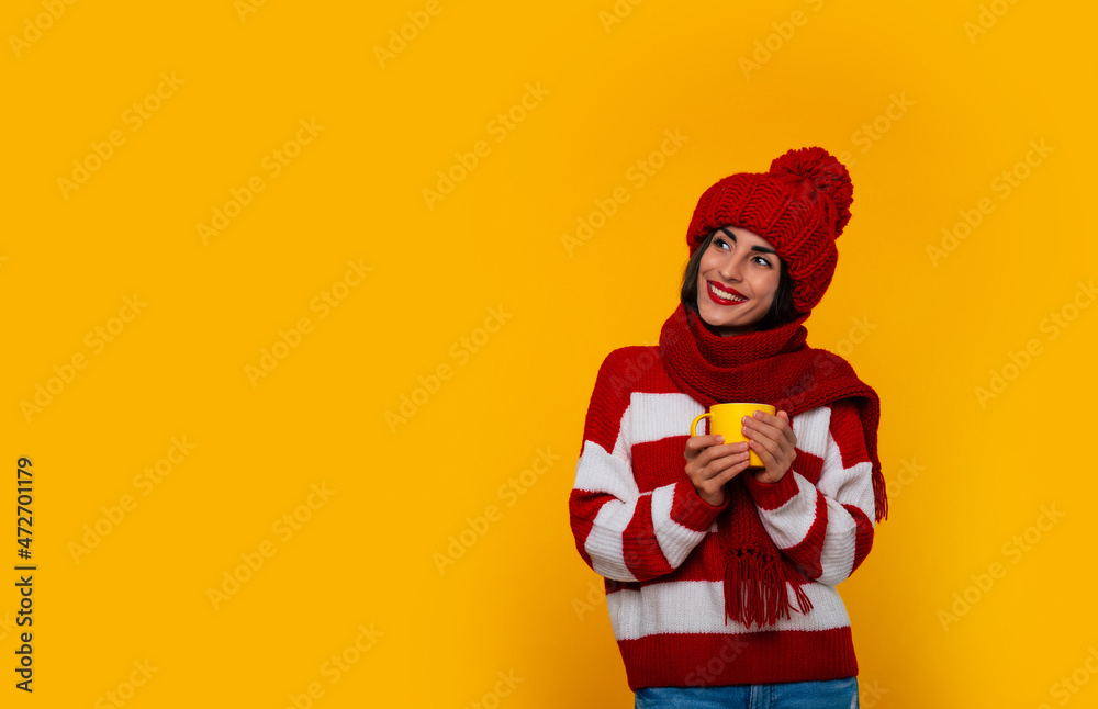 Close up photo of charming happy stylish tender woman in red winter clothes holds beverage in yellow cup in hands and relaxing