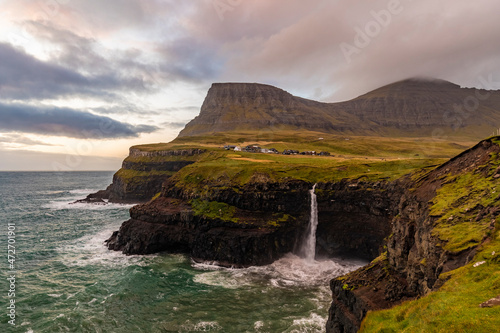 Europe, Faroe Islands. View of the village of Gasadalur and Mulafossur waterfall on the island of Vagar. photo