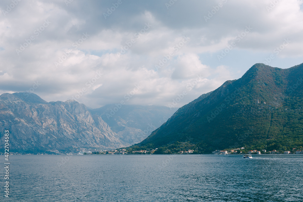 Boat sails along the Bay of Kotor against the backdrop of mountains. View from Perast