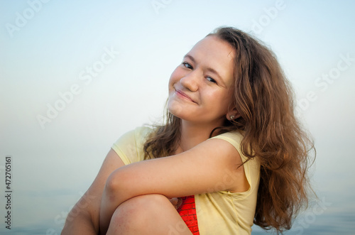 Young girl in yellow t-shirt on the sea and blue sky background, summertime, travelling, female portrait concepts