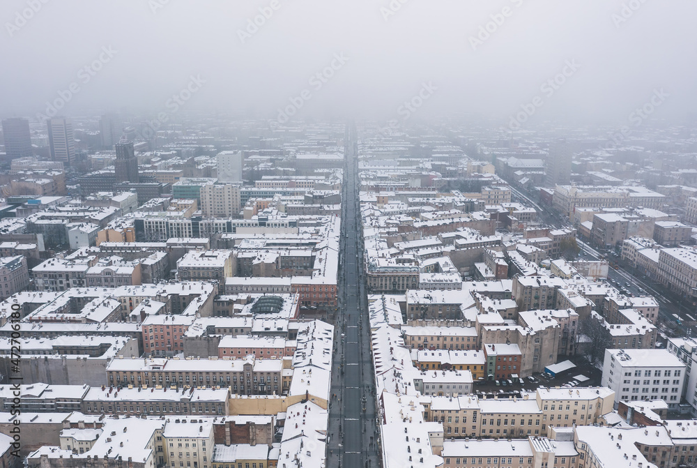 Aerial winter cityscape of Lodz, Poland. View along the famous tourist attraction - Piotrkowska Street with rooftops covered in snow.