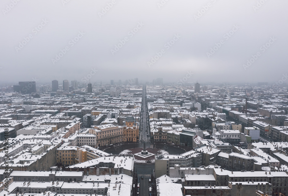 Aerial winter cityscape of Łódż, Poland.  View over the Plac Wolności and the famous tourist attraction - Piotrkowska Street with rooftops covered in snow.