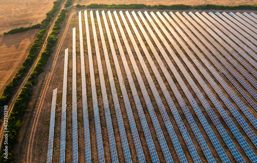 Aerial shot of ground-mounted solar panels, on a solar farm, at sunset.
